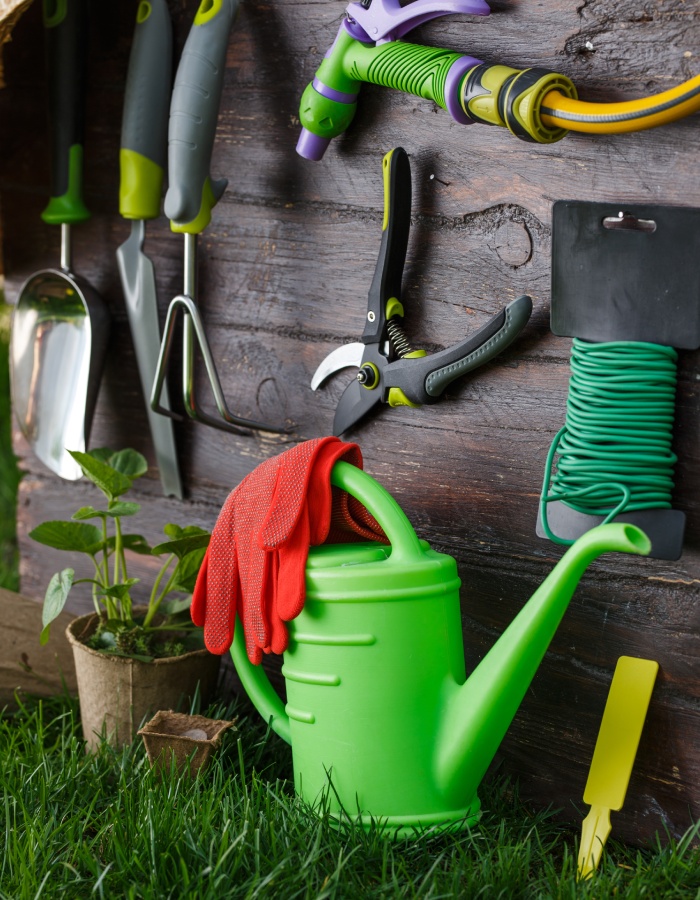 Outils et accessoires de jardinage suspendus avec arrosoir vert et gants rouges