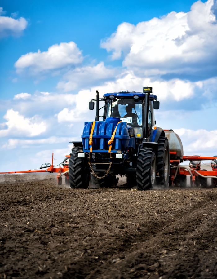 Tracteur agricole avec équipement de semis sur terrain cultivé